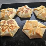 Five crunchwrap supremes crisping on outdoor griddle.