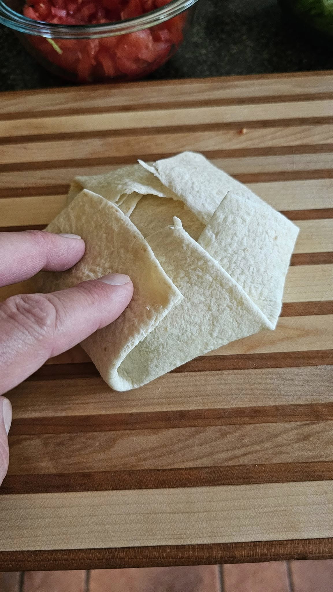 Folding large tortilla edges toward center of crunchwrap