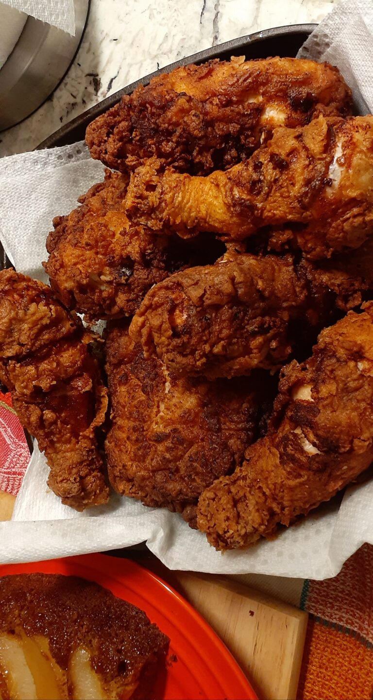 Pile of crispy buttermilk fried chicken drained on paper towels – golden brown perfection