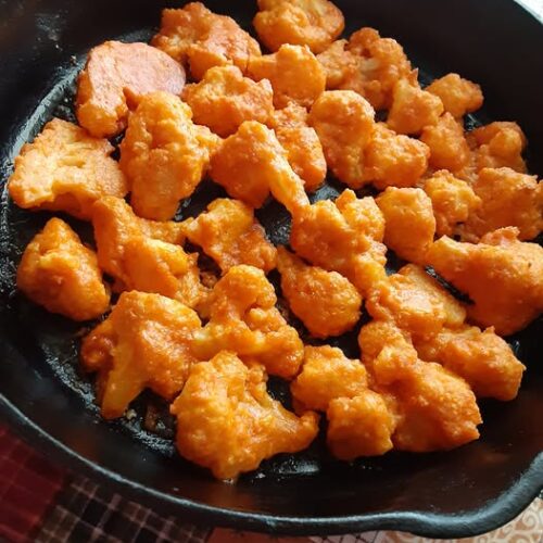 Crispy buffalo cauliflower bites plated with ranch dip and celery sticks