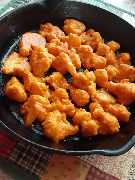 Crispy buffalo cauliflower bites plated with ranch dip and celery sticks