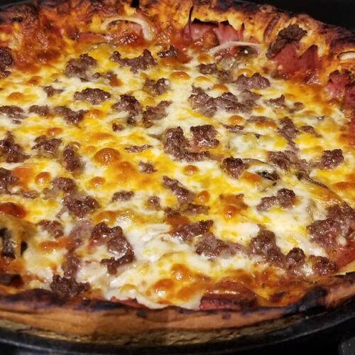 Baked cast iron deep dish pizza golden brown with bubbling cheese and crispy edges