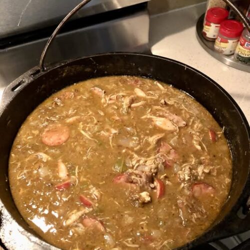 cast iron pot filled with authentic chicken and sausage gumbo simmering on stove