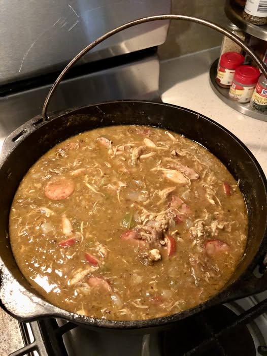 cast iron pot filled with authentic chicken and sausage gumbo simmering on stove