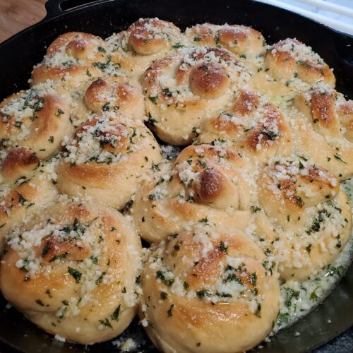 Golden brown fluffy garlic knots brushed with garlic butter and basil”