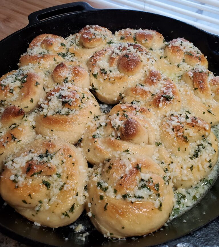 Golden brown fluffy garlic knots brushed with garlic butter and basil”