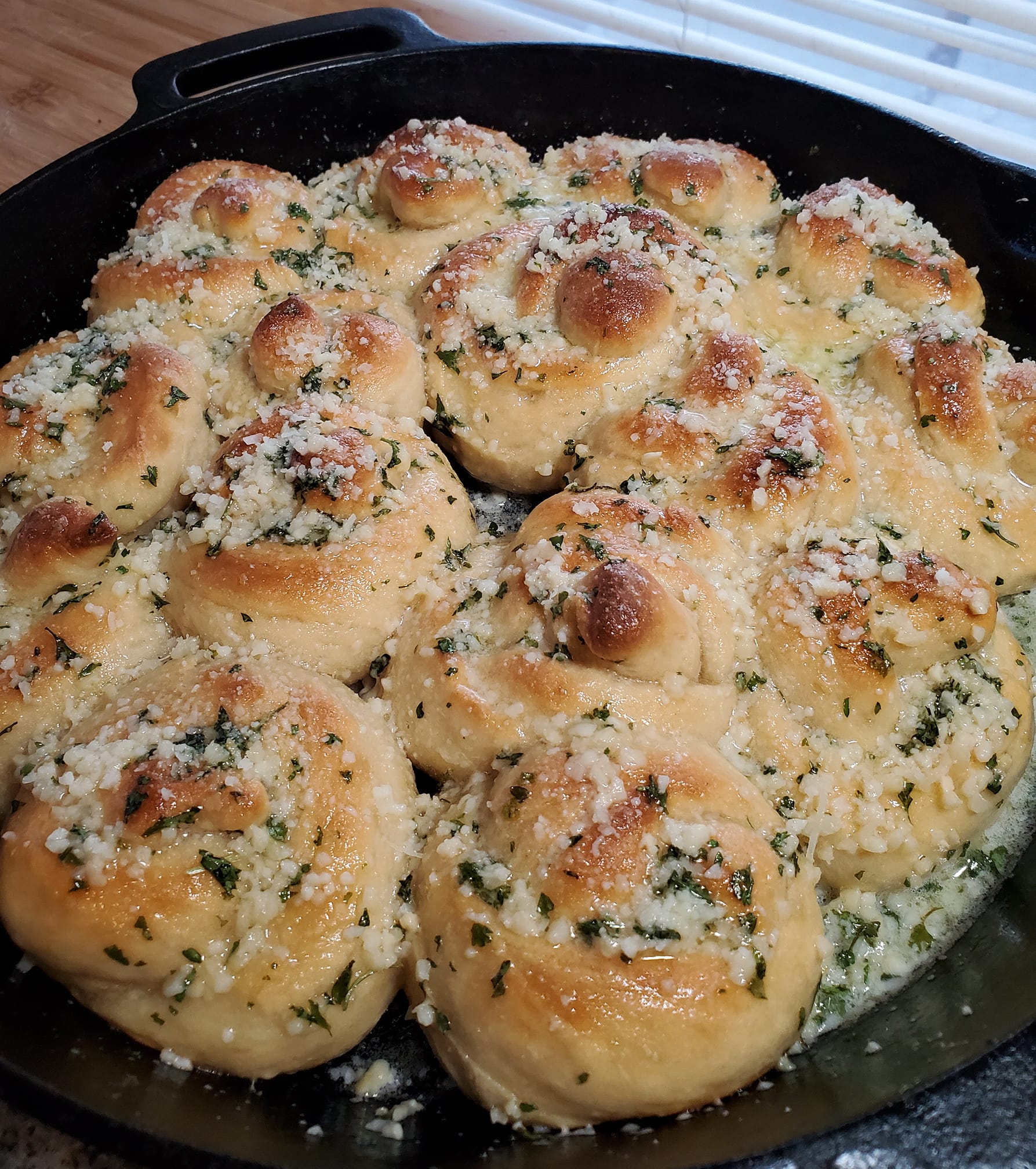 Golden brown fluffy garlic knots brushed with garlic butter and basil”