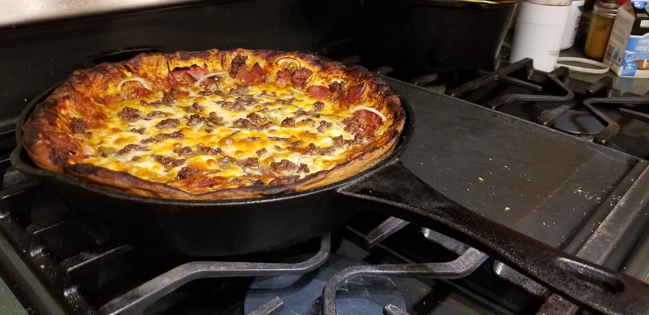 Baked cast iron deep dish pizza golden brown with bubbling cheese and crispy edges