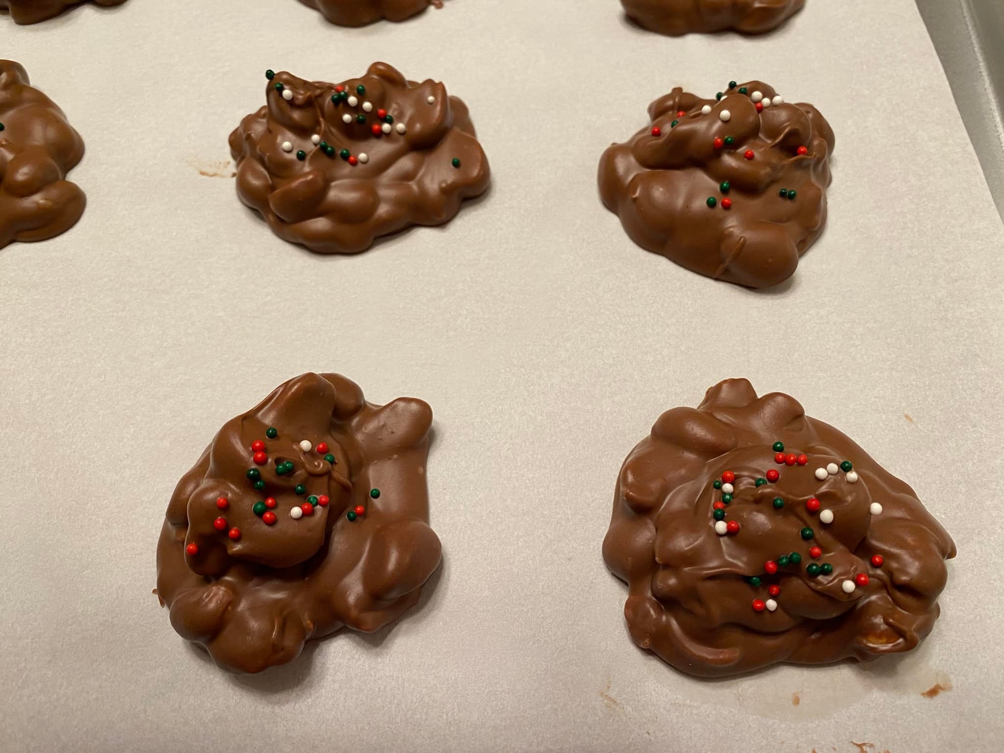 Chocolate peanut candy clusters spooned onto parchment and into festive liners