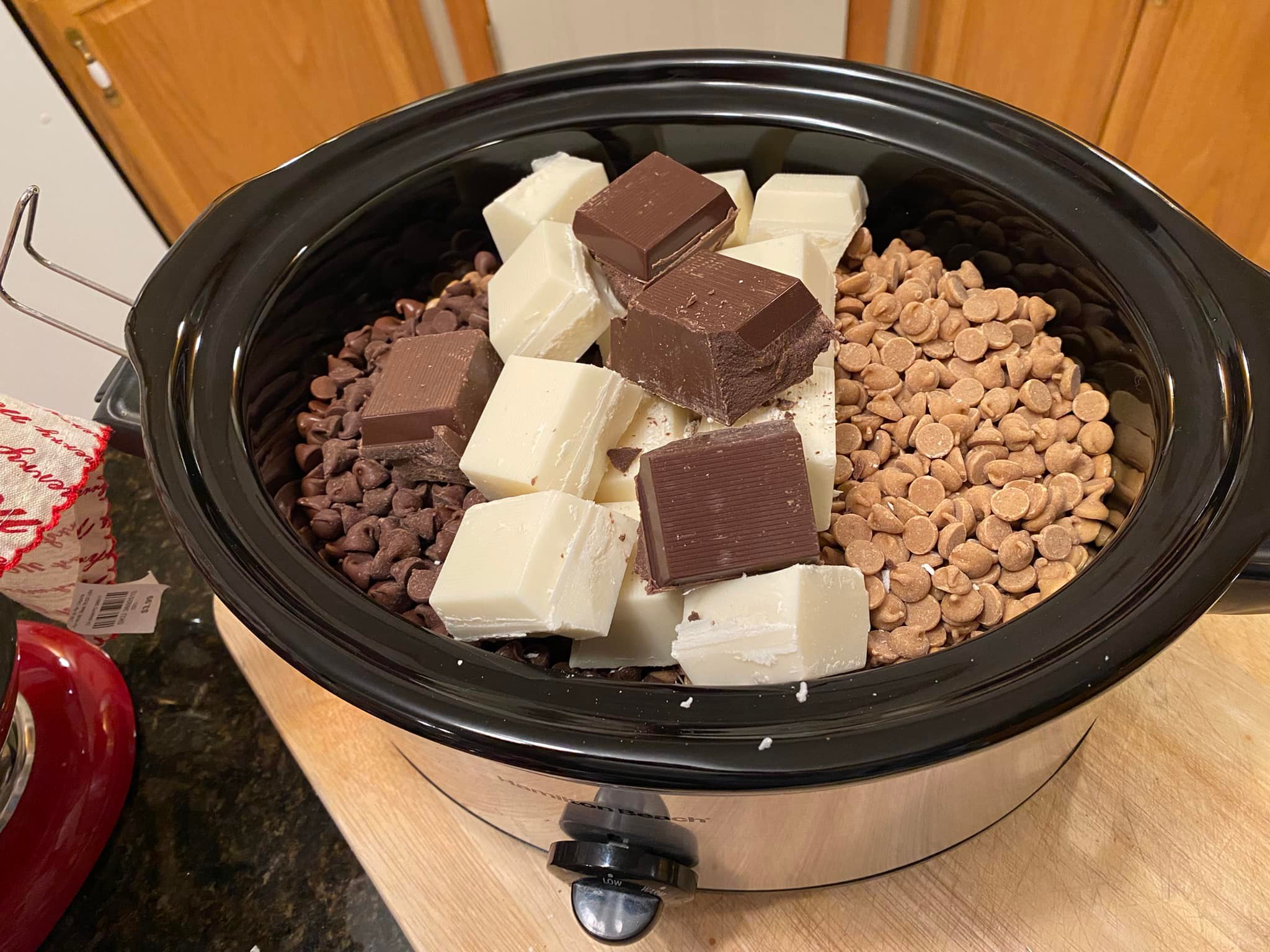 Crockpot filled with peanuts, chocolate chips, and almond bark ready to melt