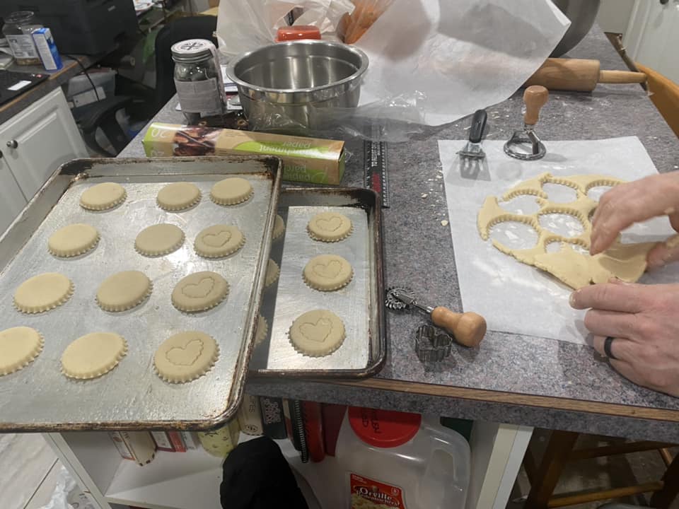 Shortbread dough being rolled out and cut into rounds with cookie cutters