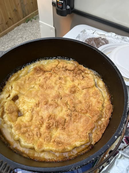 Golden brown Dutch oven peach cobbler with cake mix, freshly baked