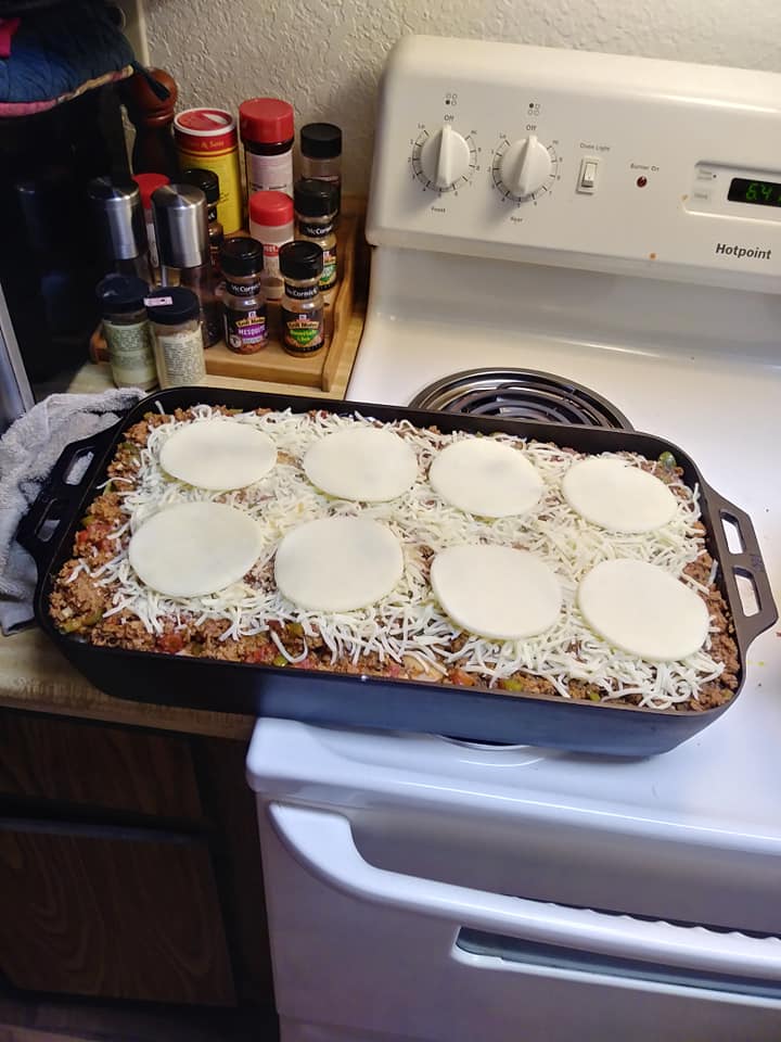 fish pan filled with layered noodles, meat sauce, cottage cheese, and provolone ready for oven]