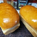 shiny golden loaves of soft white bread cooling on wire rack
