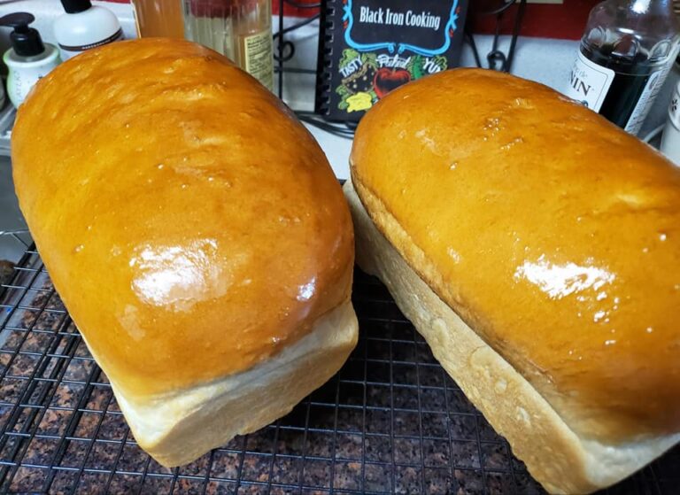 shiny golden loaves of soft white bread cooling on wire rack