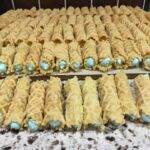 Rolled pizzelle cookies filled with blue vanilla frosting