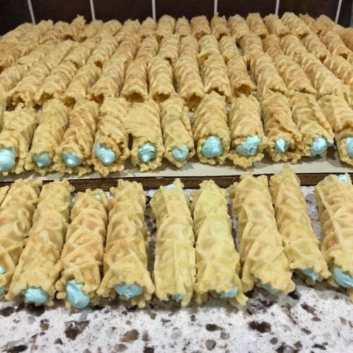 Rolled pizzelle cookies filled with blue vanilla frosting