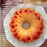 : Pineapple upside down Bundt cake flipped onto plate with cherries and pineapple