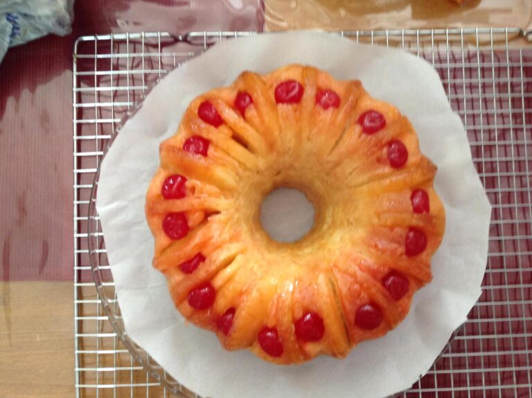 : Pineapple upside down Bundt cake flipped onto plate with cherries and pineapple