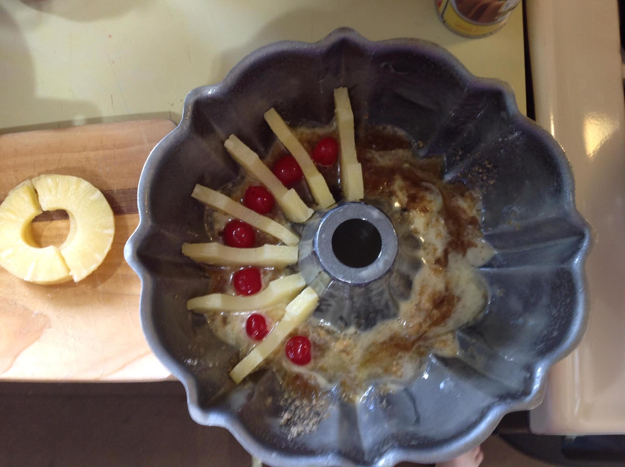 Pineapple slices and cherries arranged in Bundt pan for upside down cake