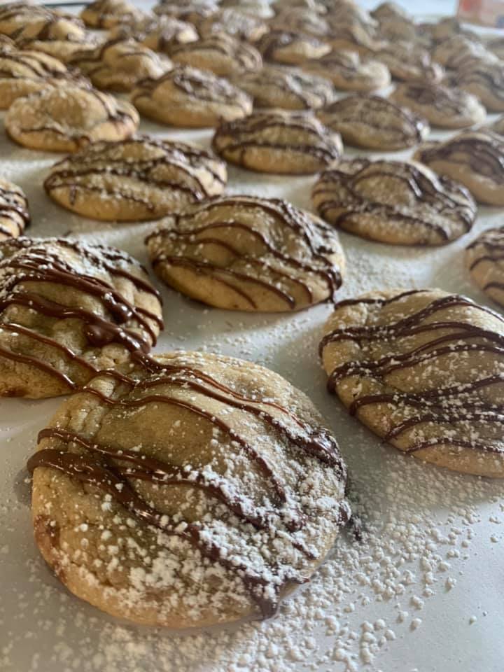 Snickers Surprise Cookies drizzled with chocolate and powdered sugar