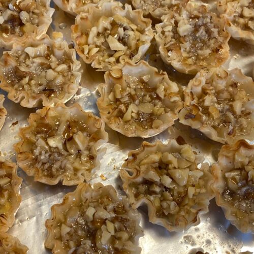 Mini baklava cups filled with nuts and honey syrup on tray