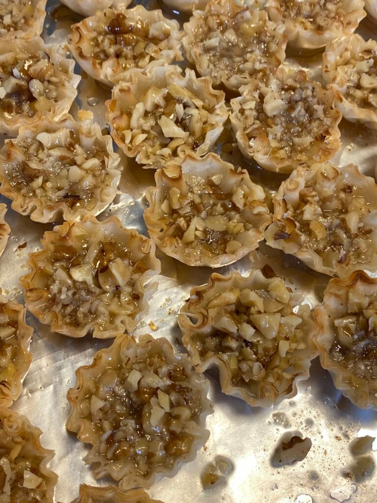 Mini baklava cups filled with nuts and honey syrup on tray