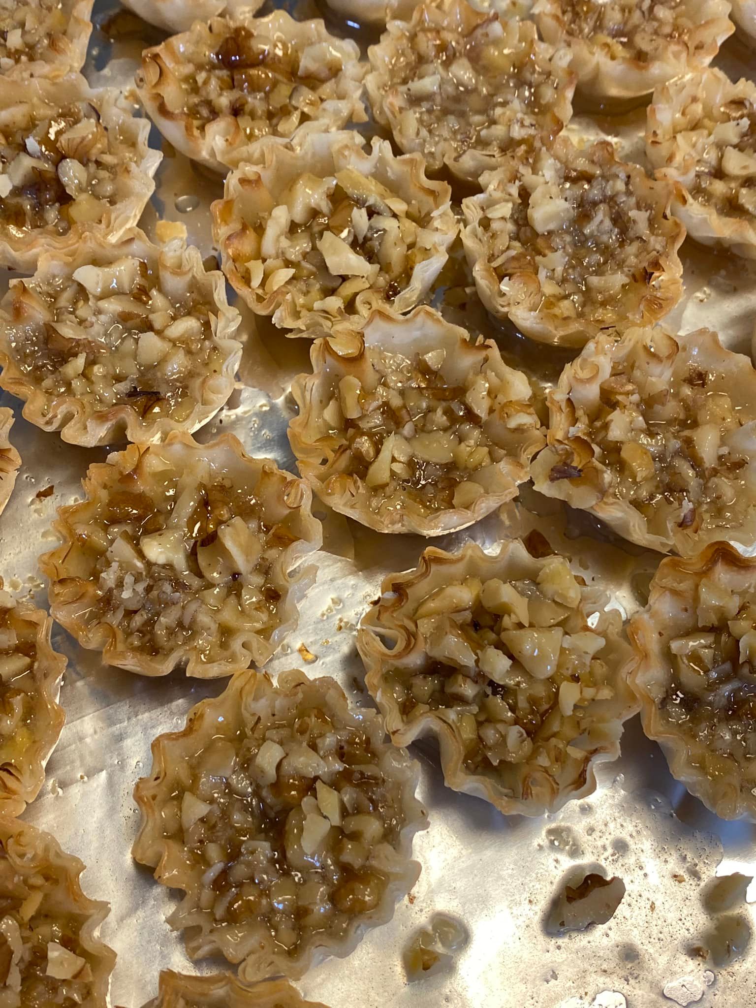 Mini baklava cups filled with nuts and honey syrup on tray