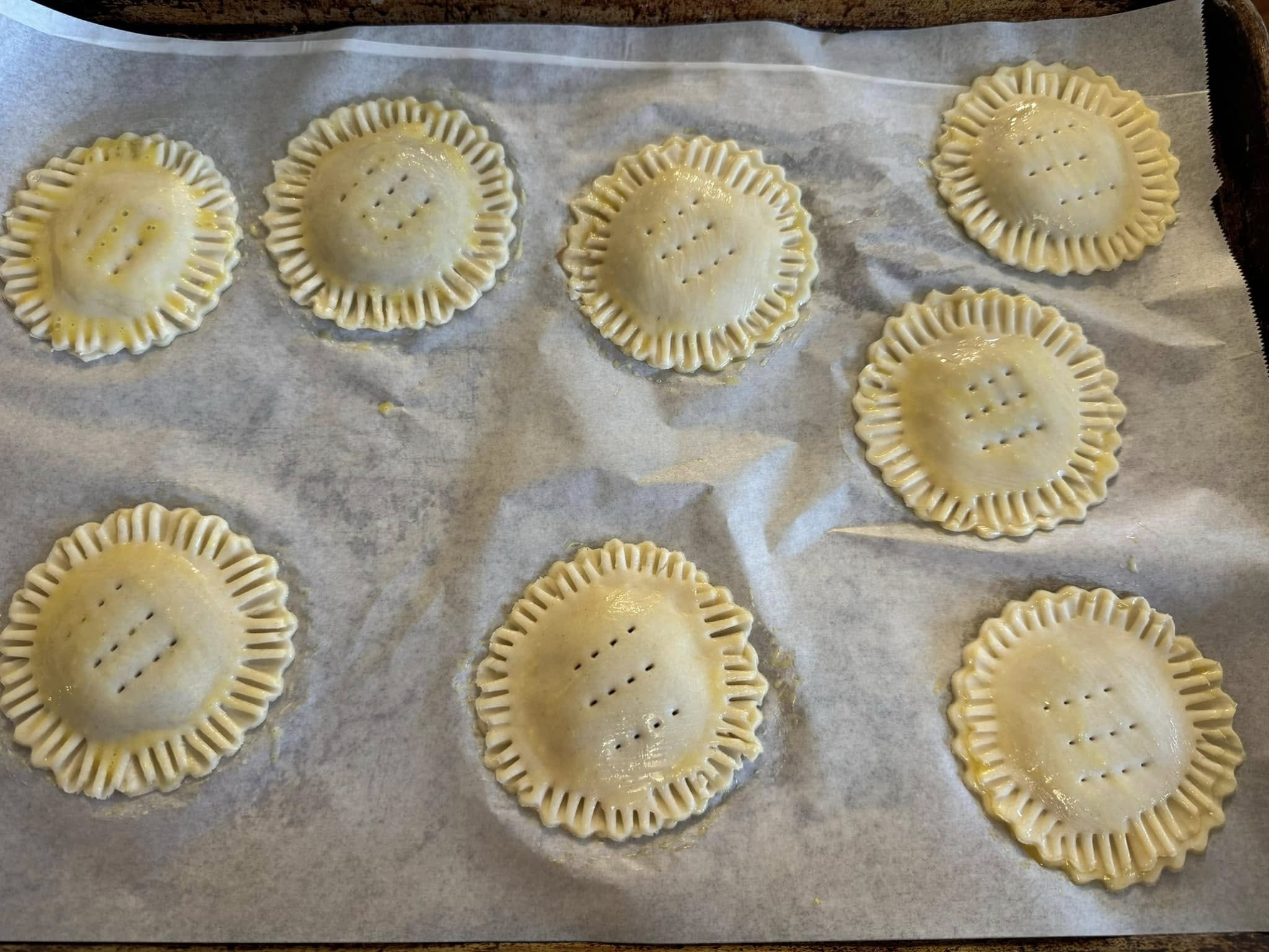 Unbaked heart-shaped pop tarts sealed with fork edges on baking sheet