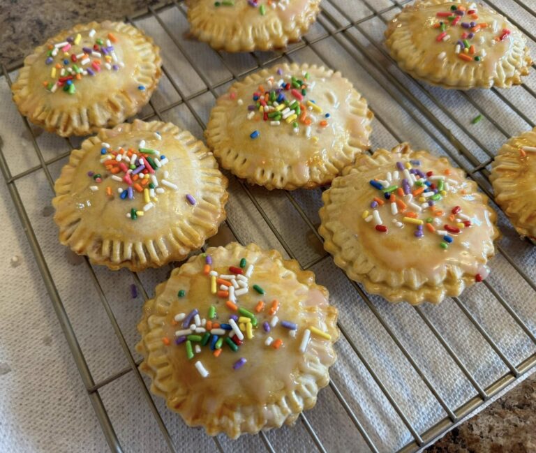 Heart-shaped pop tarts with pink icing and colorful sprinkles on cooling rack