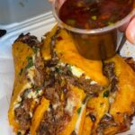 Golden birria tacos served with a side of rich red consome for dipping