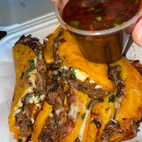 Golden birria tacos served with a side of rich red consome for dipping