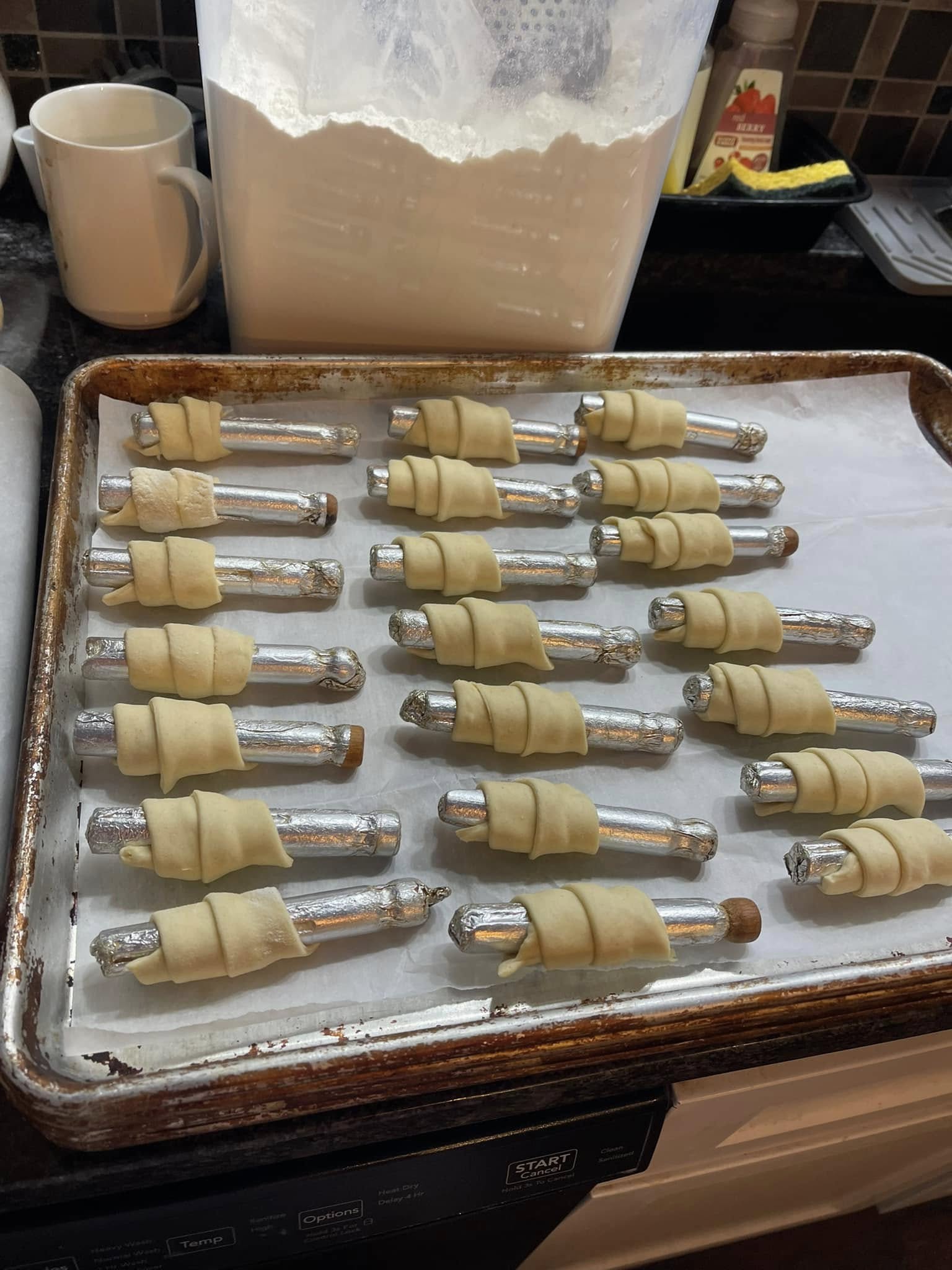 raw clothespin cookies wrapped around metal rods and lined on a baking sheet