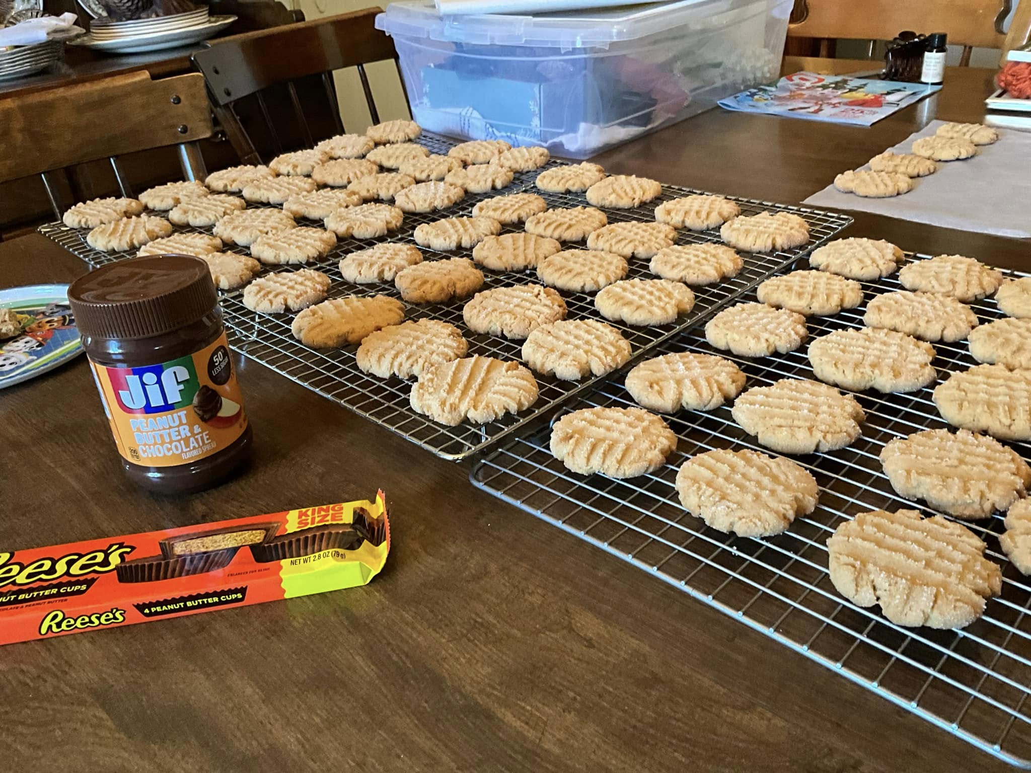 dozens of soft peanut butter cookies cooling on racks with sugar sparkle, surrounded by peanut butter and chocolate ingredients