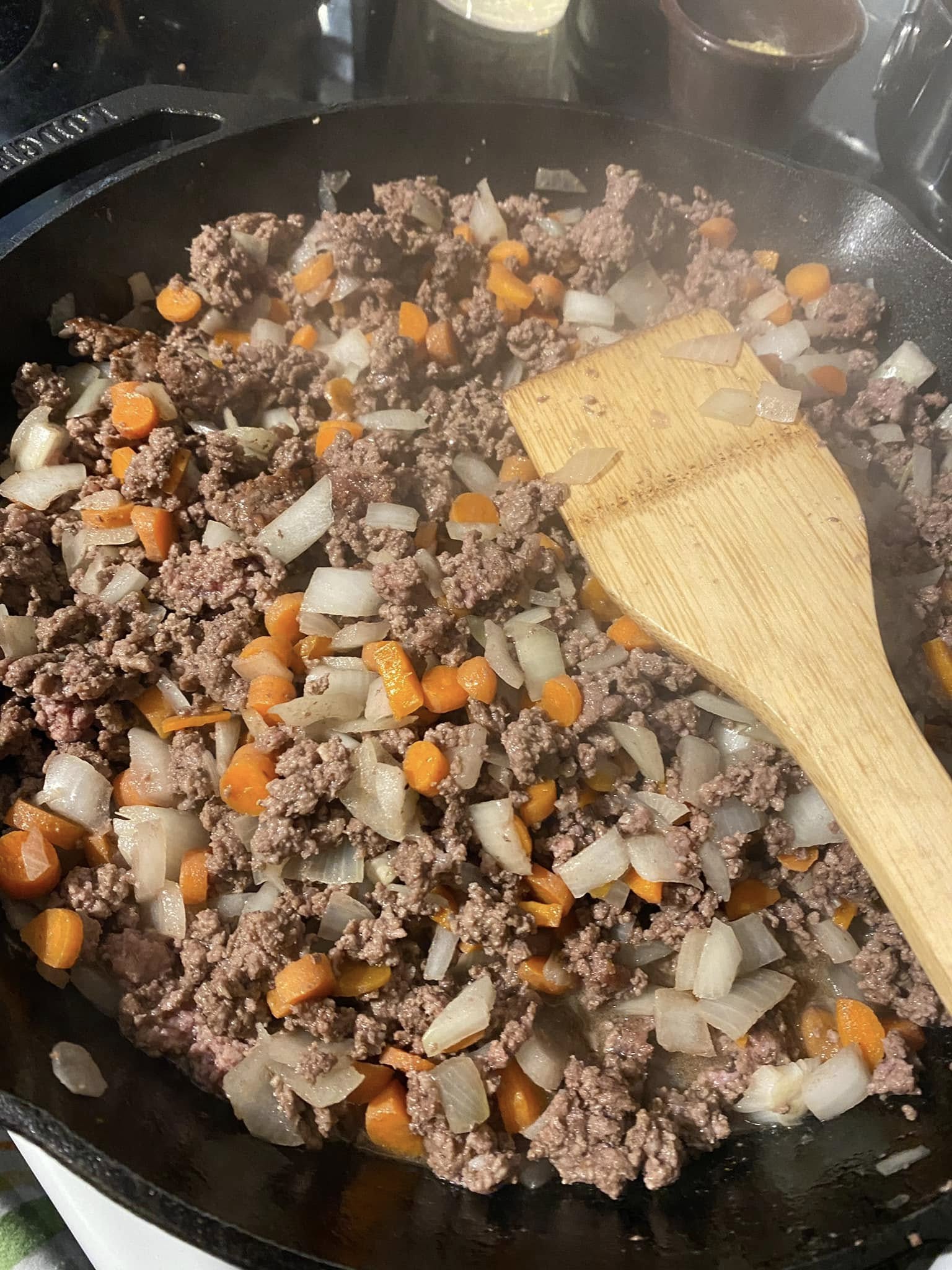raw ground beef pressed into a 12-inch cast iron skillet before browning