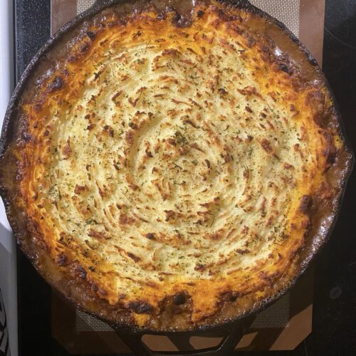 fully baked cottage pie in cast iron skillet with golden brown potato top