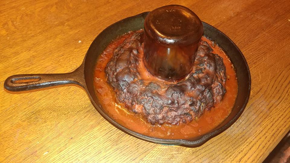 Finished smoked cast iron meatloaf with dark crust and rich tomato juices