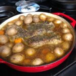 tender pot roast surrounded by potatoes and carrots simmering in broth after 3 hours of roasting