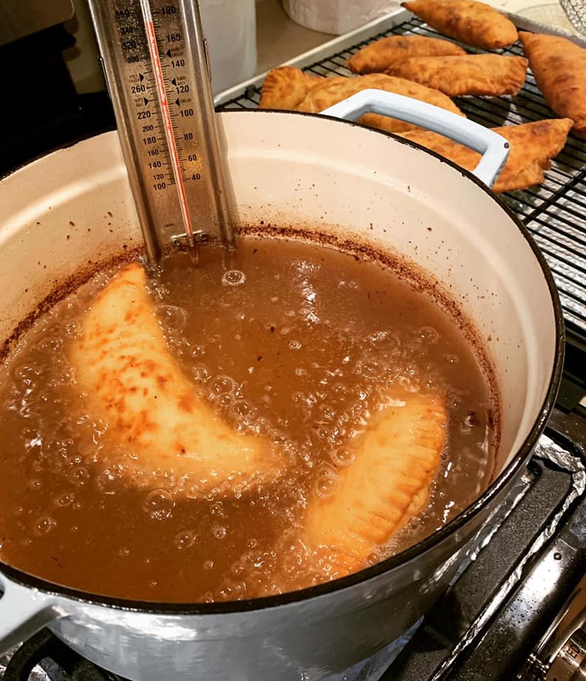 hand pies frying in a Dutch oven with a thermometer clipping onto the pot