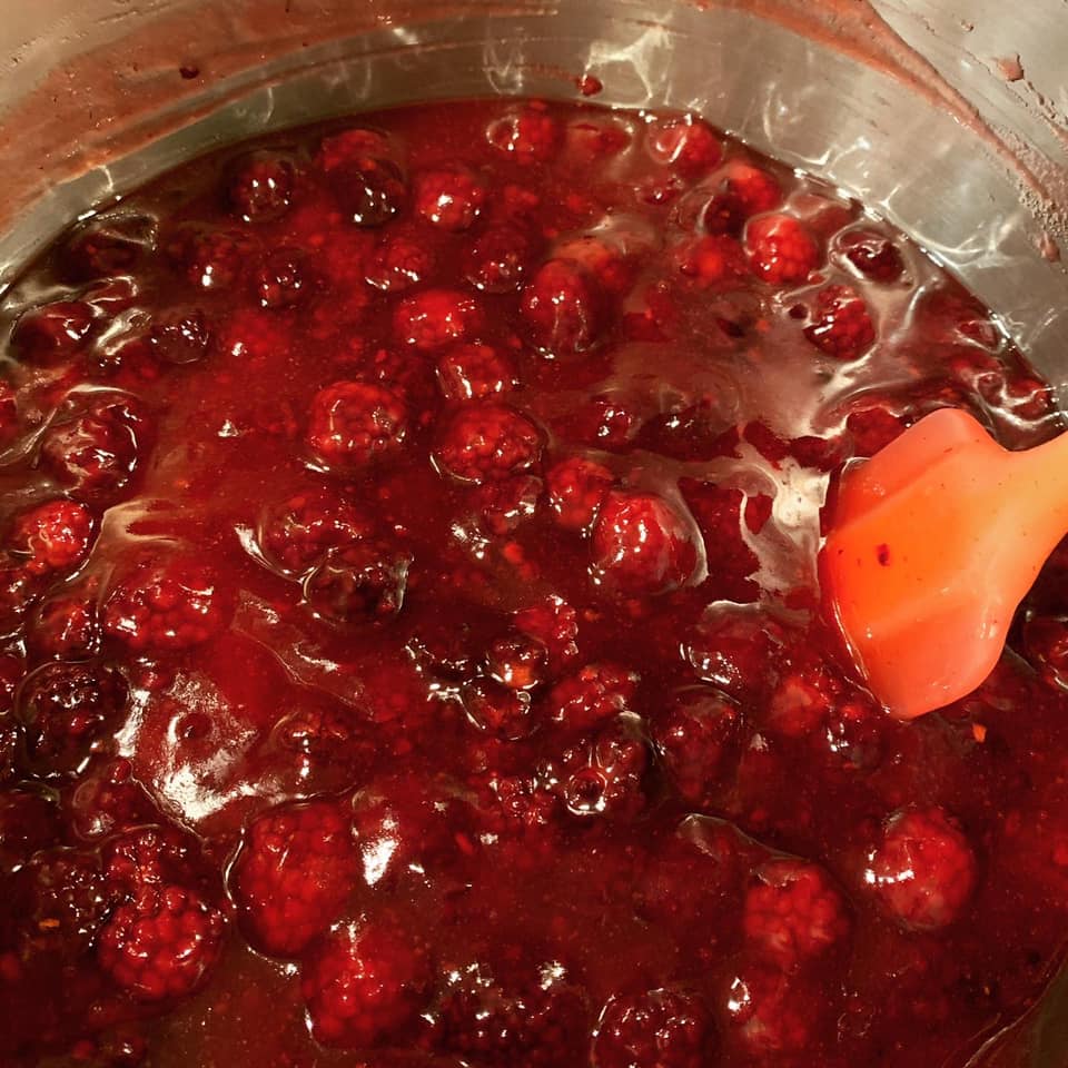 pot of simmering homemade blackberry pie filling with a spatula stirring the berries