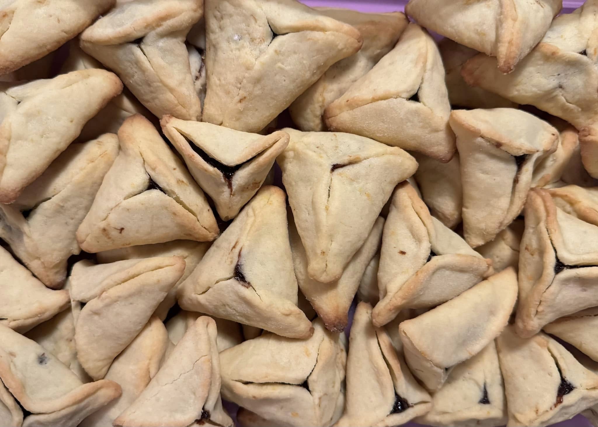 Freshly baked citrus hamantaschen arranged in a container