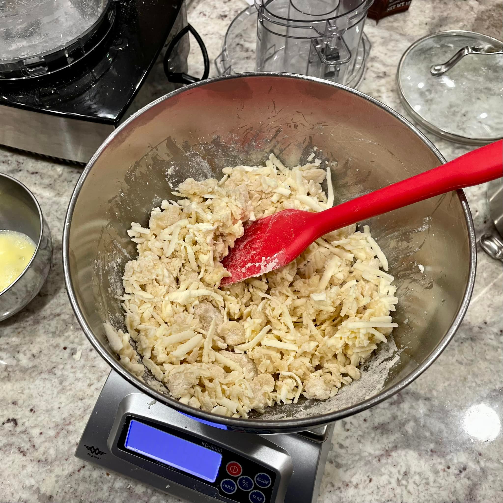 grated butter and dough mixture in a mixing bowl with a red spatula