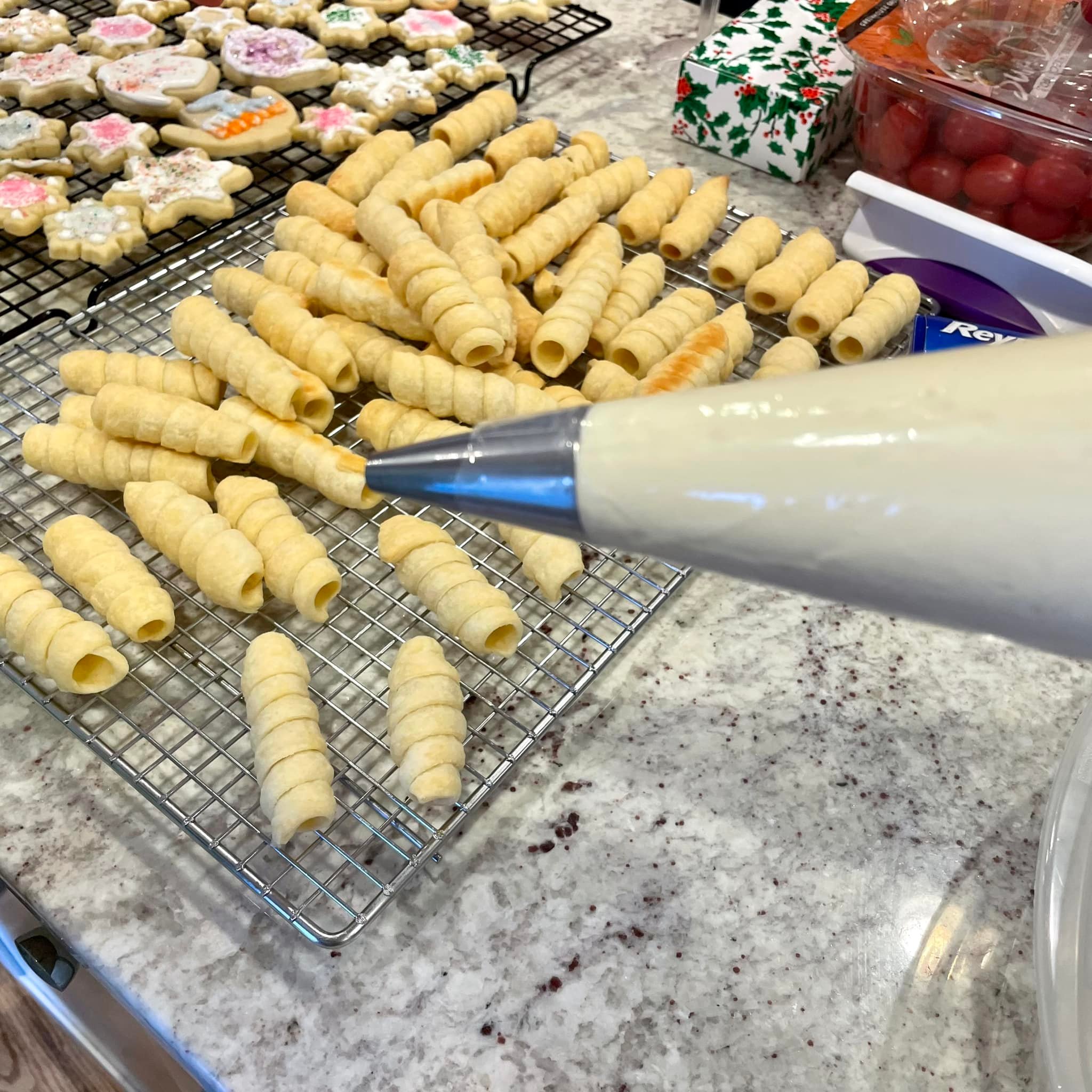 piping bag filled with Ermine icing positioned over baked lady lock shells