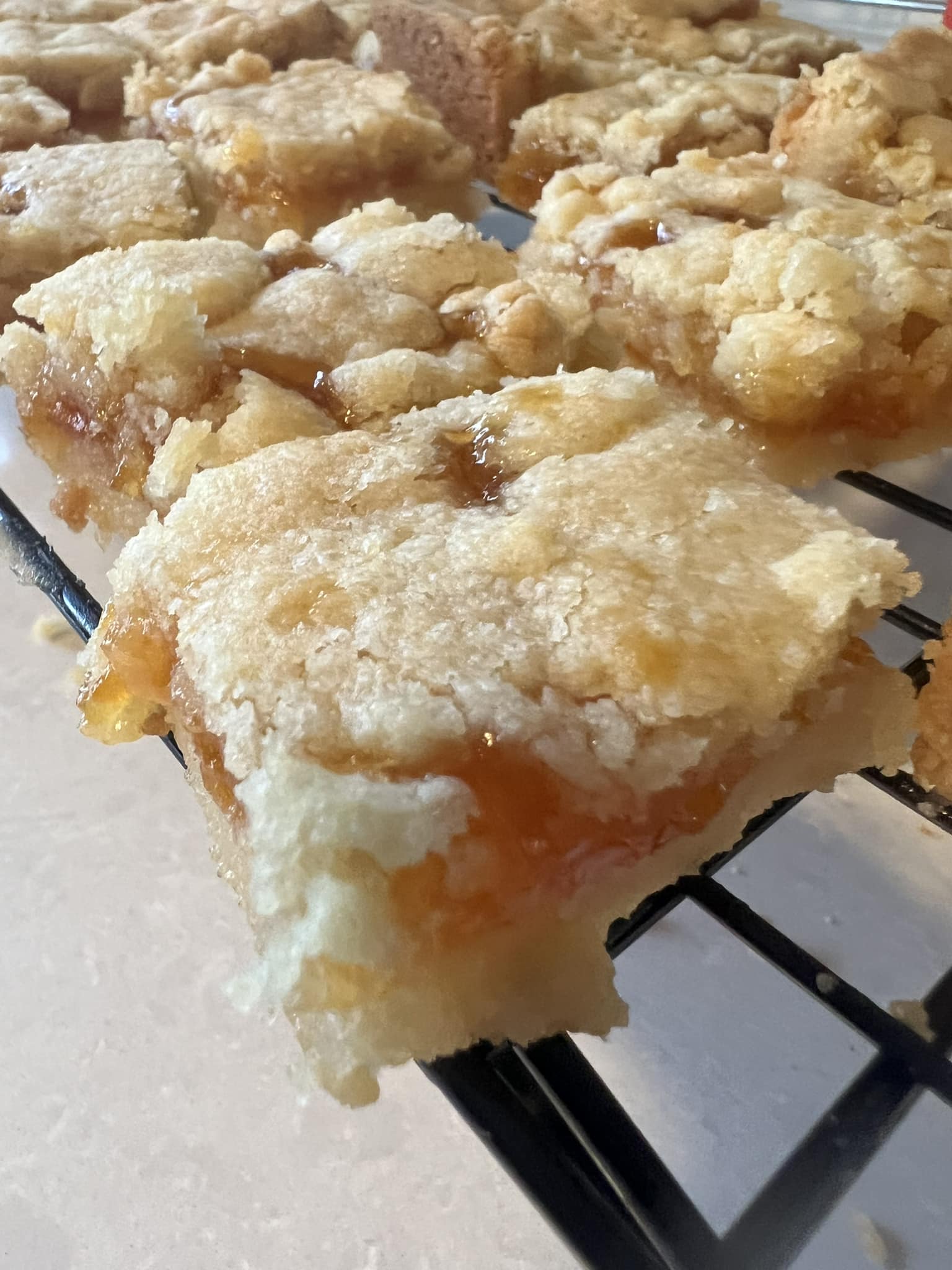 gooey apricot shortbread bar with buttery crumb topping cooling on rack