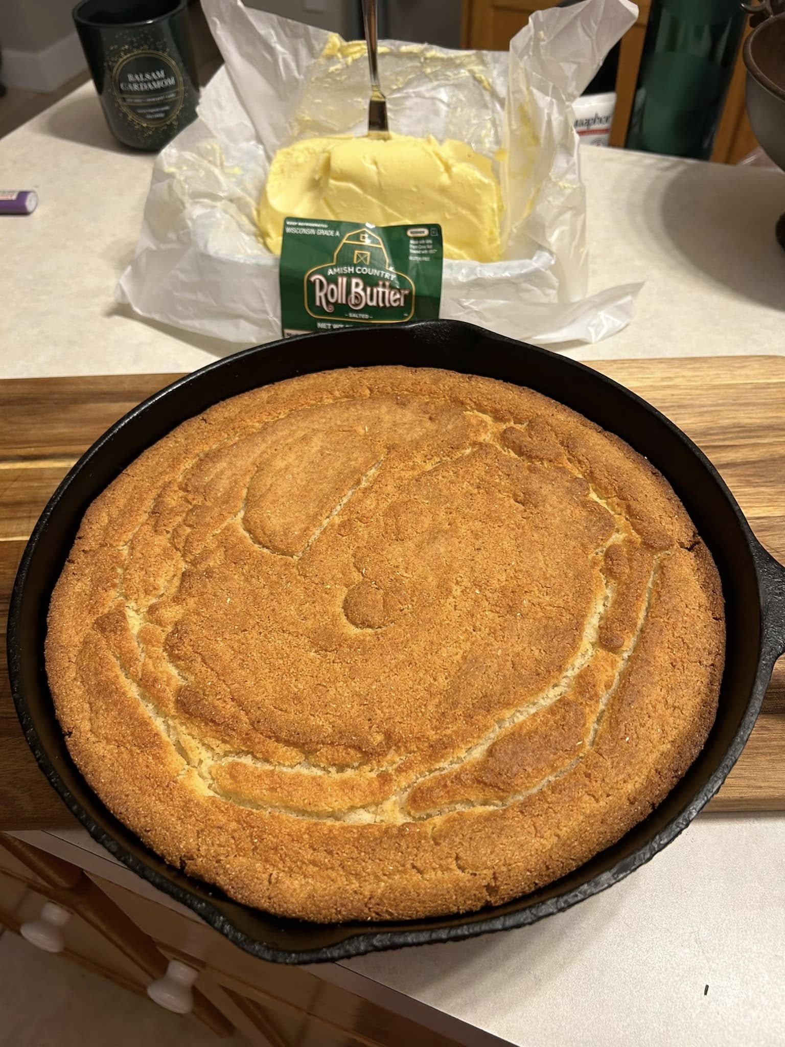 freshly baked southern buttermilk cornbread in black cast iron skillet with butter in background]