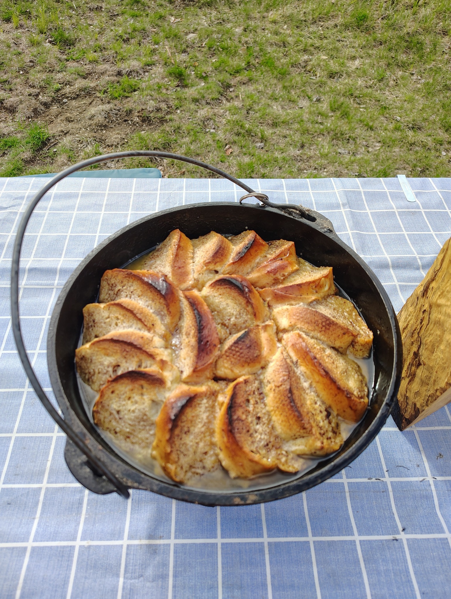 cooked Dutch oven peach French toast outdoors in a black cast iron Dutch oven with toasted bread slices arranged in a circular pattern
