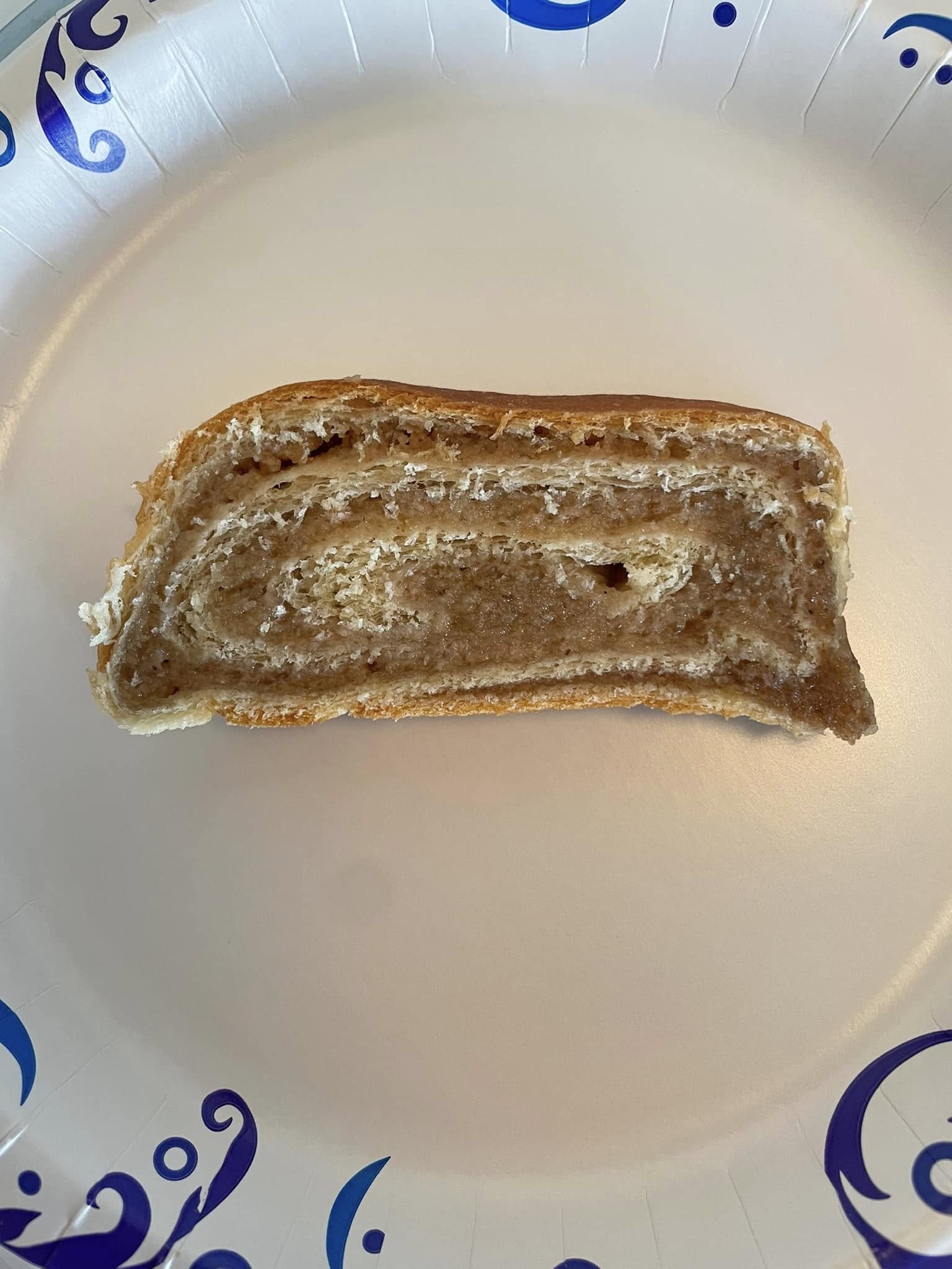 sliced Croatian nut roll showing thin layered walnut swirl on a paper plate