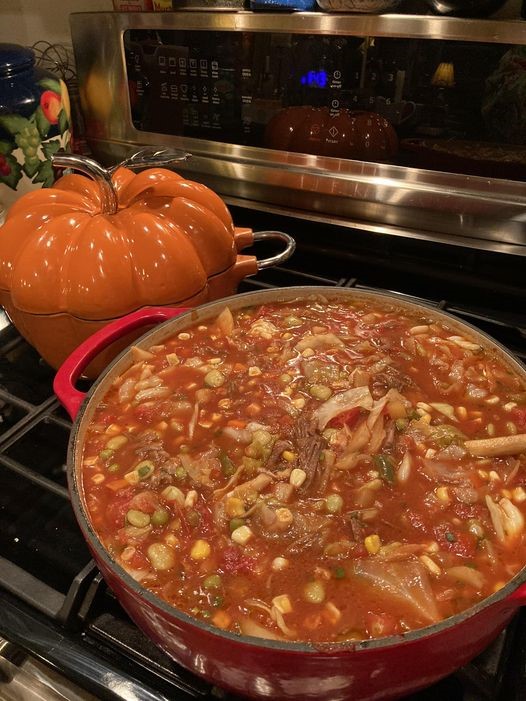 large red Dutch oven filled with old fashioned beef vegetable soup simmering on stovetop