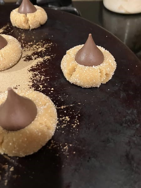 unbaked peanut butter blossom cookies rolled in sugar with Hershey’s Kisses on top before baking
