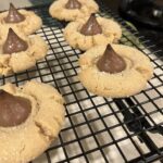 peanut butter blossom cookies cooling on a black wire rack with Hershey’s Kisses in the center